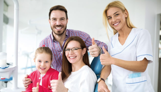 Family-in-dental-office-with-dentist-giving-thumbs-up